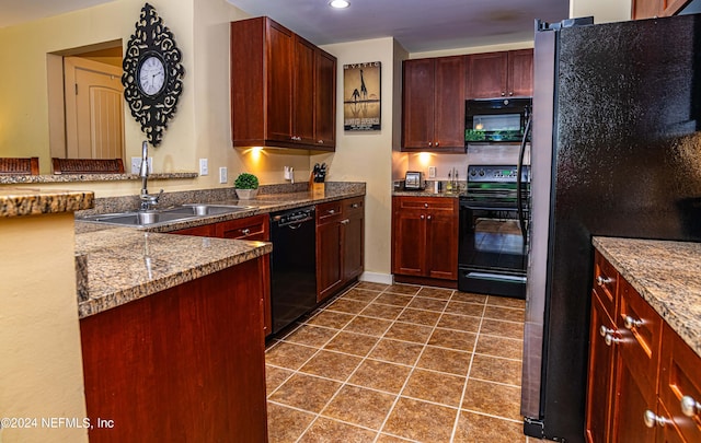 kitchen with black appliances, dark tile patterned floors, sink, and stone counters