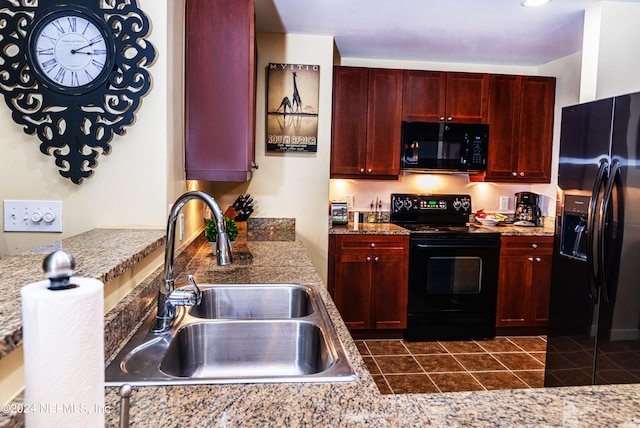 kitchen with black appliances, dark tile patterned floors, and sink