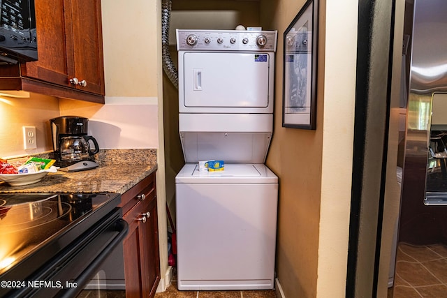 clothes washing area with stacked washer / drying machine and tile patterned floors