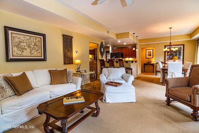 carpeted living room with ceiling fan with notable chandelier