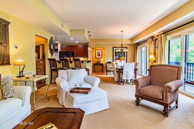 living room with light colored carpet and an inviting chandelier