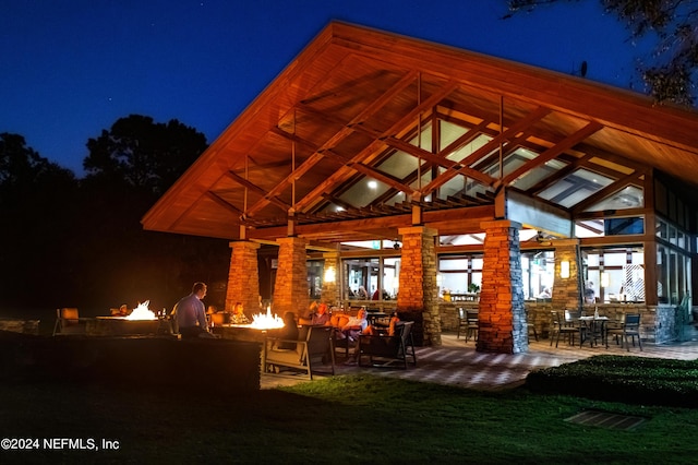 back house at night featuring a fire pit and a patio