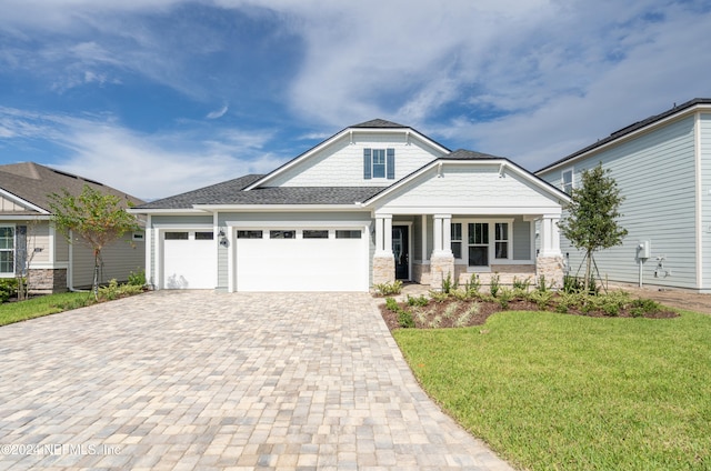 craftsman-style house with a front lawn, covered porch, and a garage