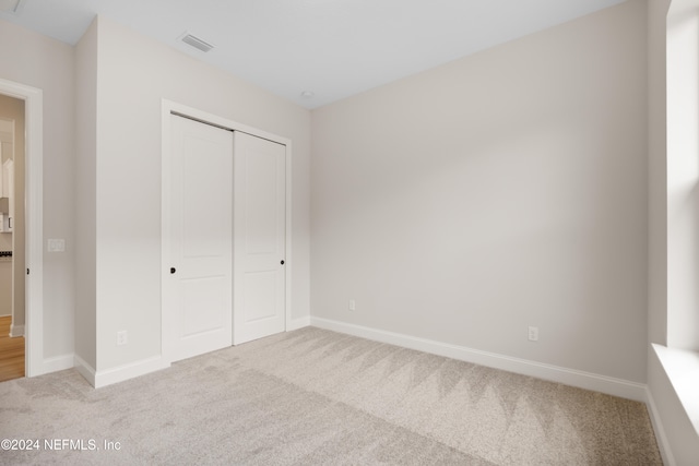 unfurnished bedroom featuring light colored carpet and a closet