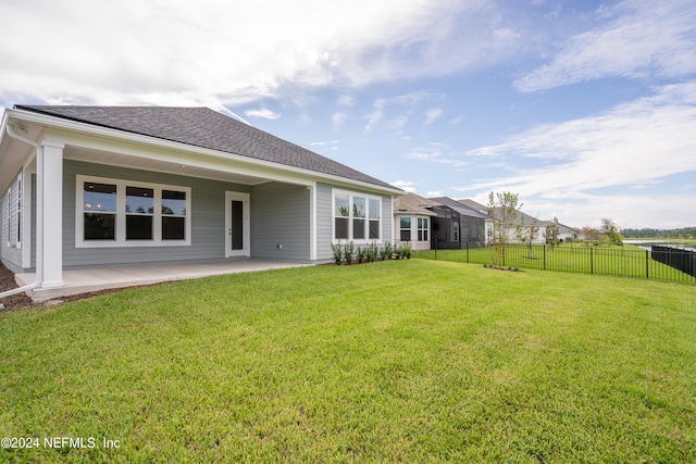 rear view of house featuring a lawn and a patio