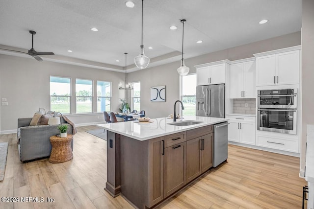 kitchen featuring a center island with sink, sink, white cabinetry, and stainless steel appliances