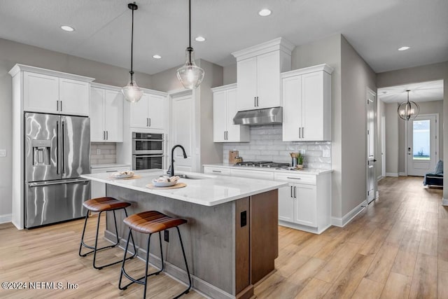 kitchen with white cabinets, pendant lighting, and stainless steel appliances