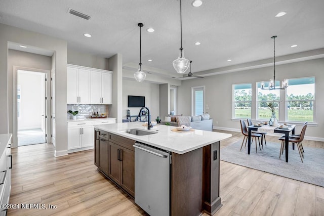 kitchen featuring pendant lighting, white cabinetry, stainless steel dishwasher, and sink