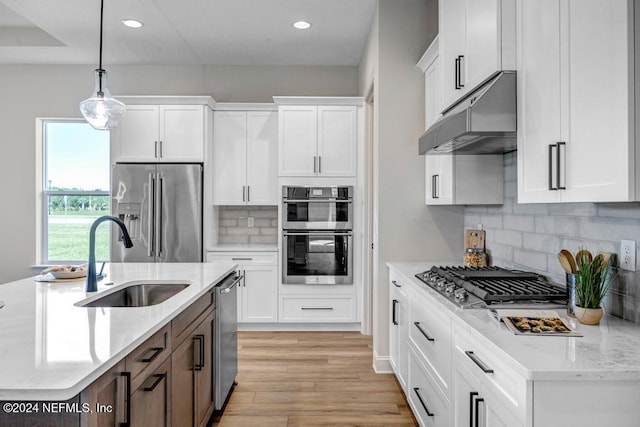 kitchen with white cabinets, decorative light fixtures, sink, and appliances with stainless steel finishes