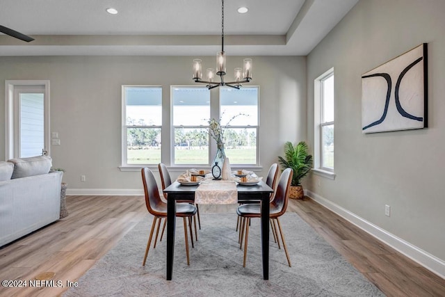 dining space with a wealth of natural light, light hardwood / wood-style flooring, and a notable chandelier