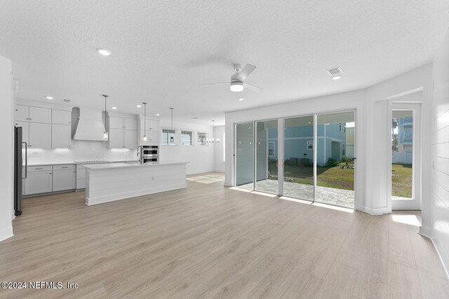 unfurnished living room featuring a textured ceiling, light hardwood / wood-style flooring, and ceiling fan