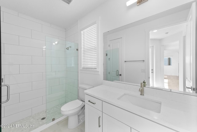 bathroom featuring a shower with door, vanity, and toilet