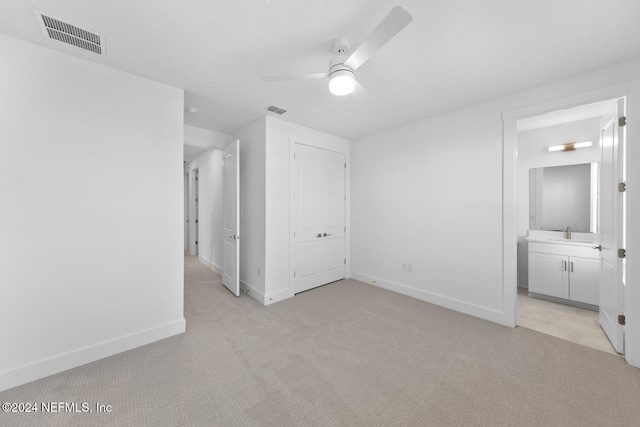 unfurnished bedroom with ceiling fan, light colored carpet, connected bathroom, and a closet