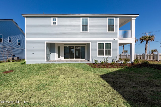 rear view of property with a yard, a balcony, and cooling unit