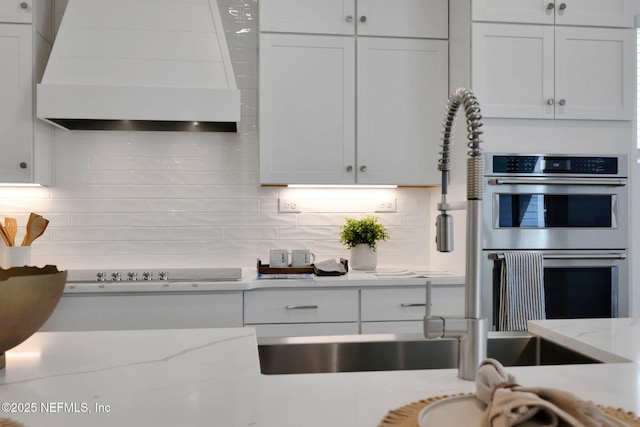 25 Seaside Vista Ct, Saint Augustine, FL 32084 - kitchen featuring wall chimney exhaust hood, double oven, decorative backsplash, and white cabinets