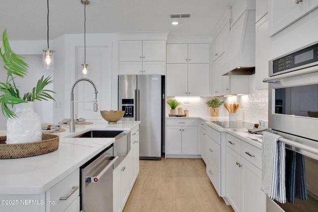 25 Seaside Vista Ct, Saint Augustine, FL 32084 - kitchen featuring stainless steel appliances, a sink, premium range hood, light wood finished floors, and white cabinetry