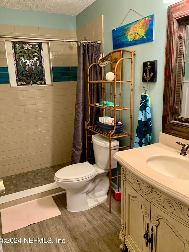 bathroom with wood-type flooring, vanity, toilet, a textured ceiling, and a shower with curtain