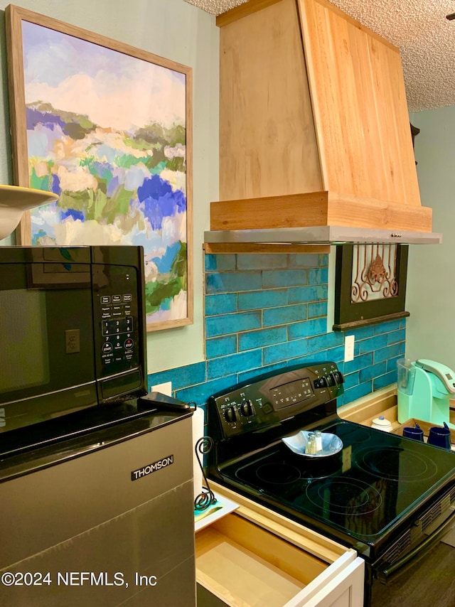 kitchen featuring custom exhaust hood, a textured ceiling, light brown cabinetry, backsplash, and black appliances