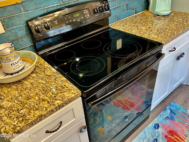 interior details featuring black electric range, tasteful backsplash, and wood-type flooring