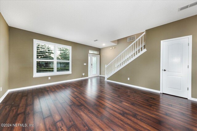 unfurnished living room featuring a textured ceiling and dark wood-type flooring