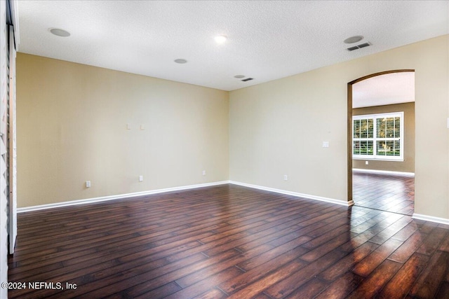 empty room with dark hardwood / wood-style floors and a textured ceiling