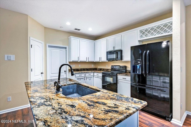 kitchen with dark hardwood / wood-style floors, a center island with sink, sink, black appliances, and white cabinets