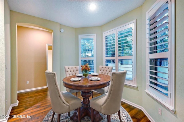 dining area featuring a textured ceiling, plenty of natural light, and dark hardwood / wood-style floors