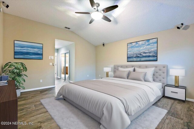 bedroom with lofted ceiling, a textured ceiling, hardwood / wood-style flooring, and ceiling fan