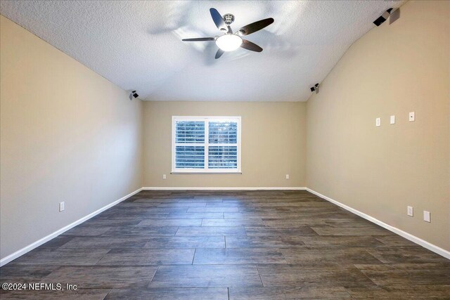 empty room featuring ceiling fan, a textured ceiling, lofted ceiling, and dark hardwood / wood-style floors