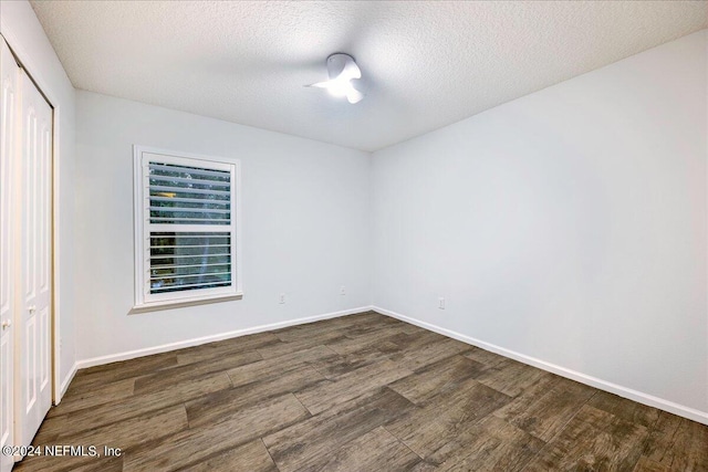 empty room featuring a textured ceiling and dark hardwood / wood-style flooring