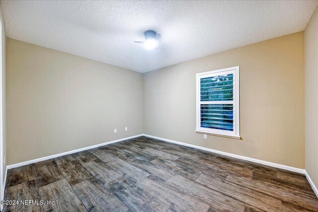 empty room featuring dark wood-type flooring and a textured ceiling