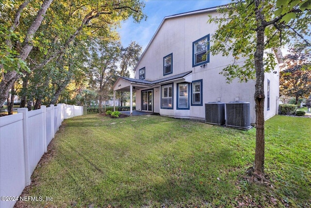 rear view of house featuring a yard, a patio, and central AC unit