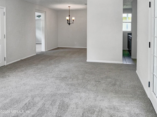 unfurnished room with a chandelier and light colored carpet