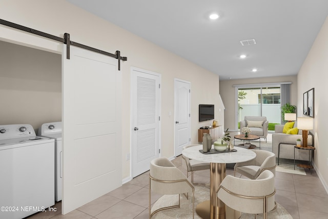 tiled dining area featuring a barn door and independent washer and dryer