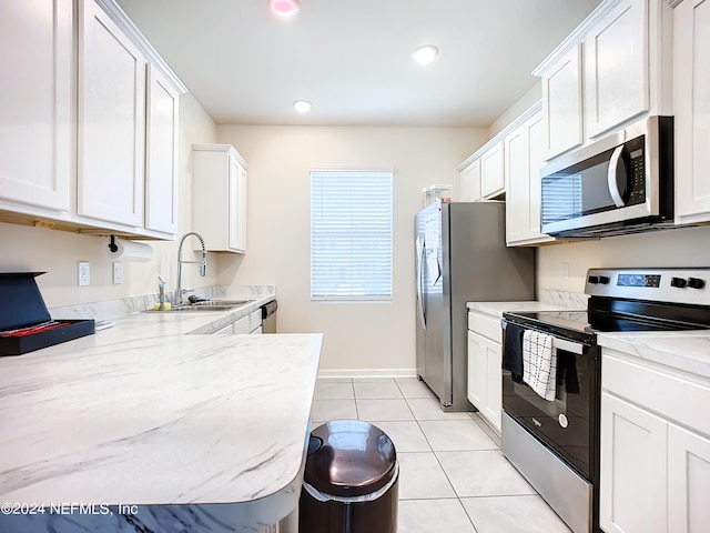 kitchen featuring white cabinetry, light tile patterned floors, light stone countertops, appliances with stainless steel finishes, and sink