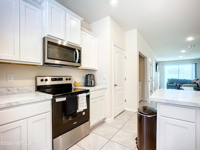 kitchen with appliances with stainless steel finishes, light tile patterned floors, and white cabinets