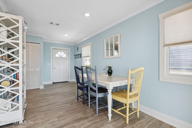 dining space with wood-type flooring, a wealth of natural light, and ornamental molding