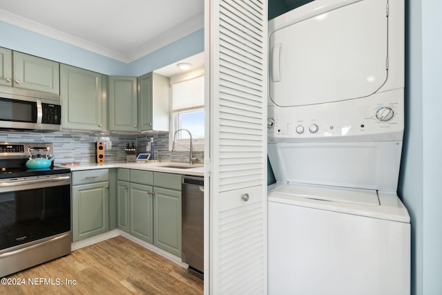 clothes washing area with light hardwood / wood-style flooring, stacked washing maching and dryer, and sink