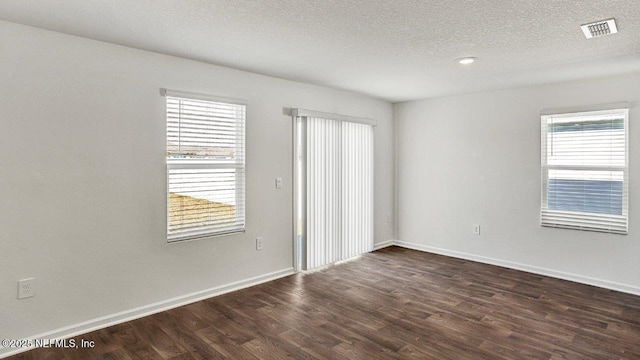 unfurnished room featuring dark wood-type flooring, a textured ceiling, and a wealth of natural light