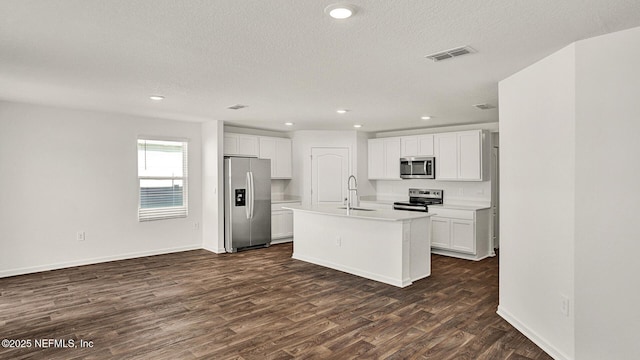 kitchen with sink, dark hardwood / wood-style flooring, stainless steel appliances, a kitchen island with sink, and white cabinets