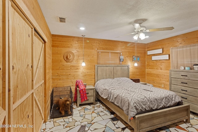 bedroom featuring ceiling fan, wood walls, and a textured ceiling