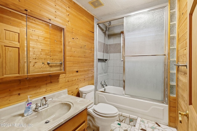 full bathroom featuring a textured ceiling, tile floors, toilet, wood walls, and shower / bath combination with glass door