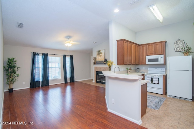 kitchen with light wood-type flooring, white appliances, a textured ceiling, kitchen peninsula, and ceiling fan