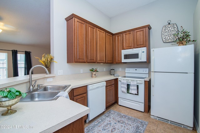 kitchen with a textured ceiling, white appliances, kitchen peninsula, sink, and light tile patterned flooring