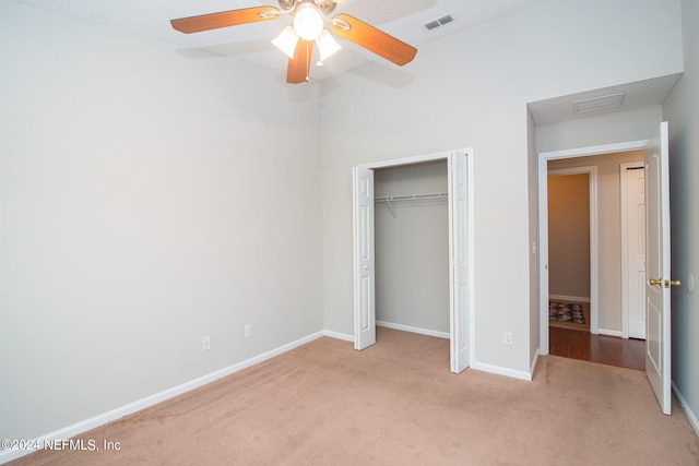 unfurnished bedroom with light carpet, a textured ceiling, ceiling fan, and a closet