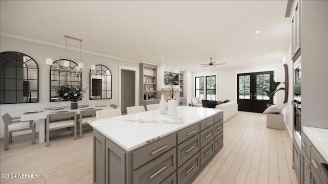 kitchen with light stone countertops, french doors, built in features, pendant lighting, and a kitchen island