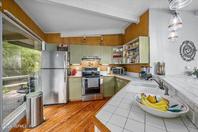 kitchen featuring sink, stainless steel appliances, light hardwood / wood-style flooring, tile counters, and green cabinets