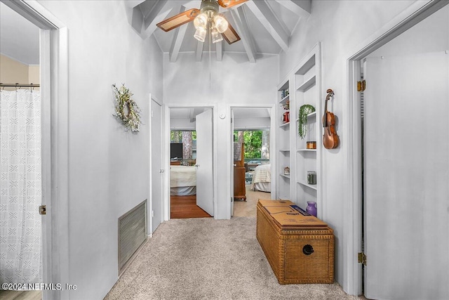 hallway with built in features, light carpet, high vaulted ceiling, and beam ceiling