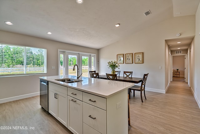 kitchen featuring sink, dishwasher, light wood-type flooring, lofted ceiling, and a center island with sink