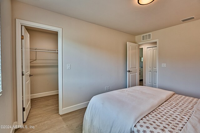 bedroom featuring a spacious closet, a closet, and light wood-type flooring